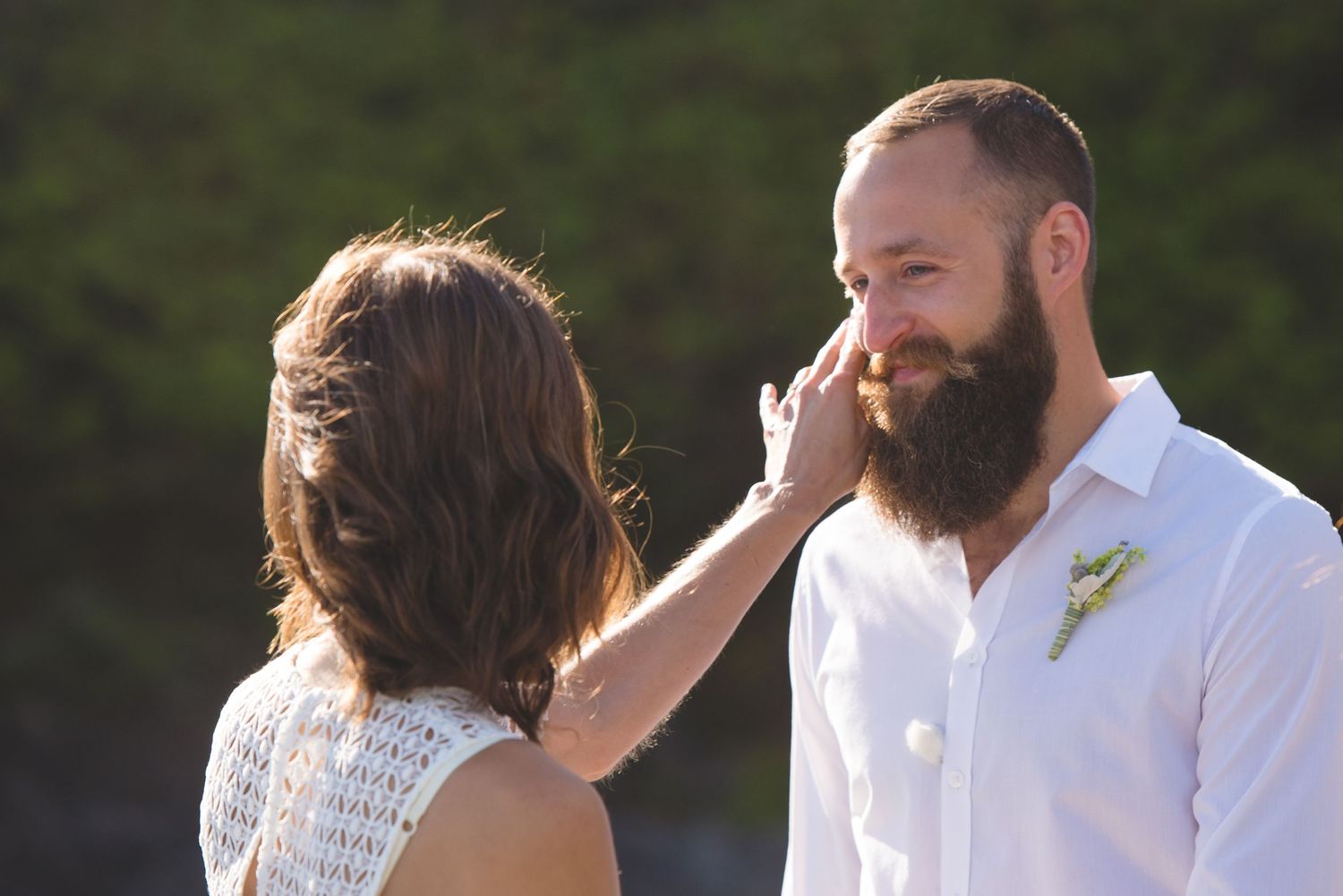 A couple shares a romantic moment in an outdoor setting during a wedding celebration.