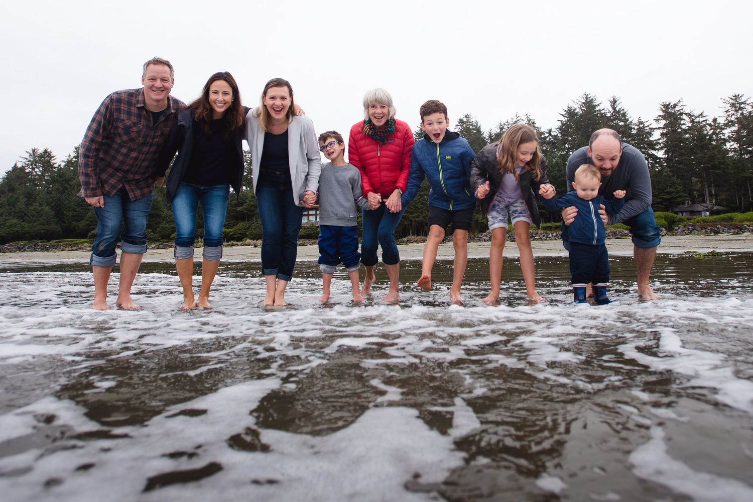 Group lined up at the beach with their feet in the water at low tide.