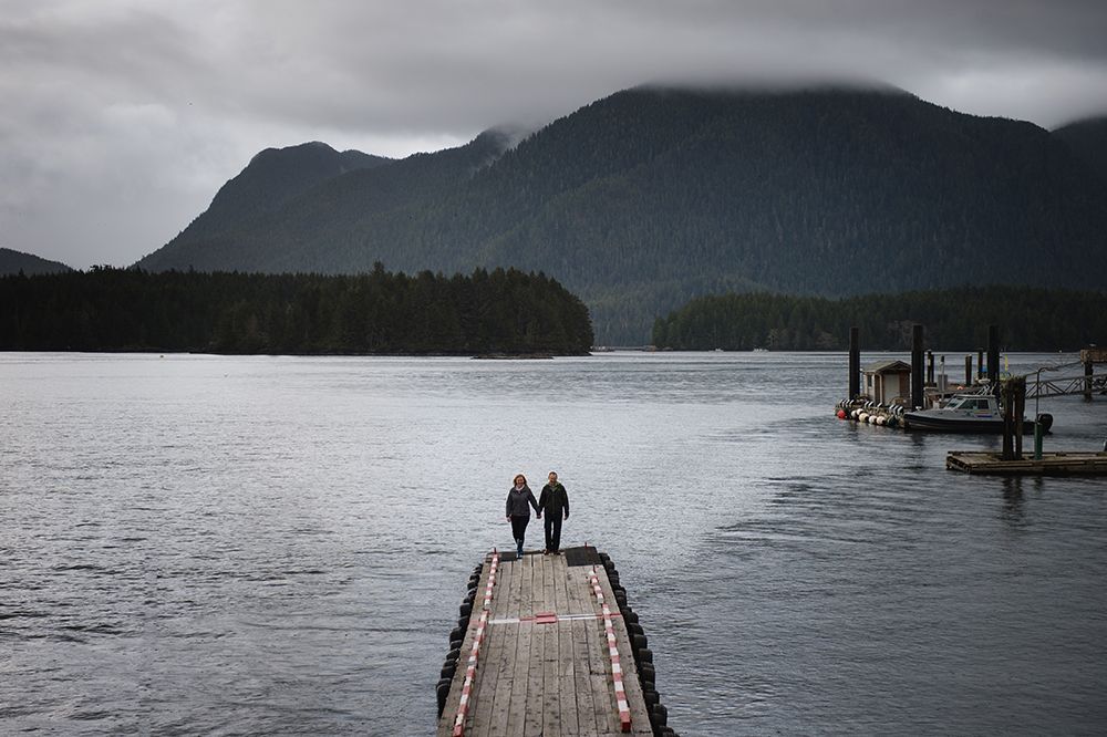 A series of wooden docks extend into a misty lake surrounded by mountains on an overcast day.