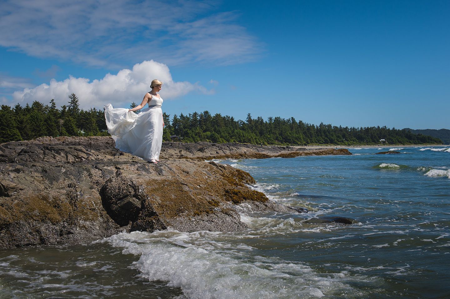 Dramatic coastal scene with waves crashing against rocky shoreline under blue sky.