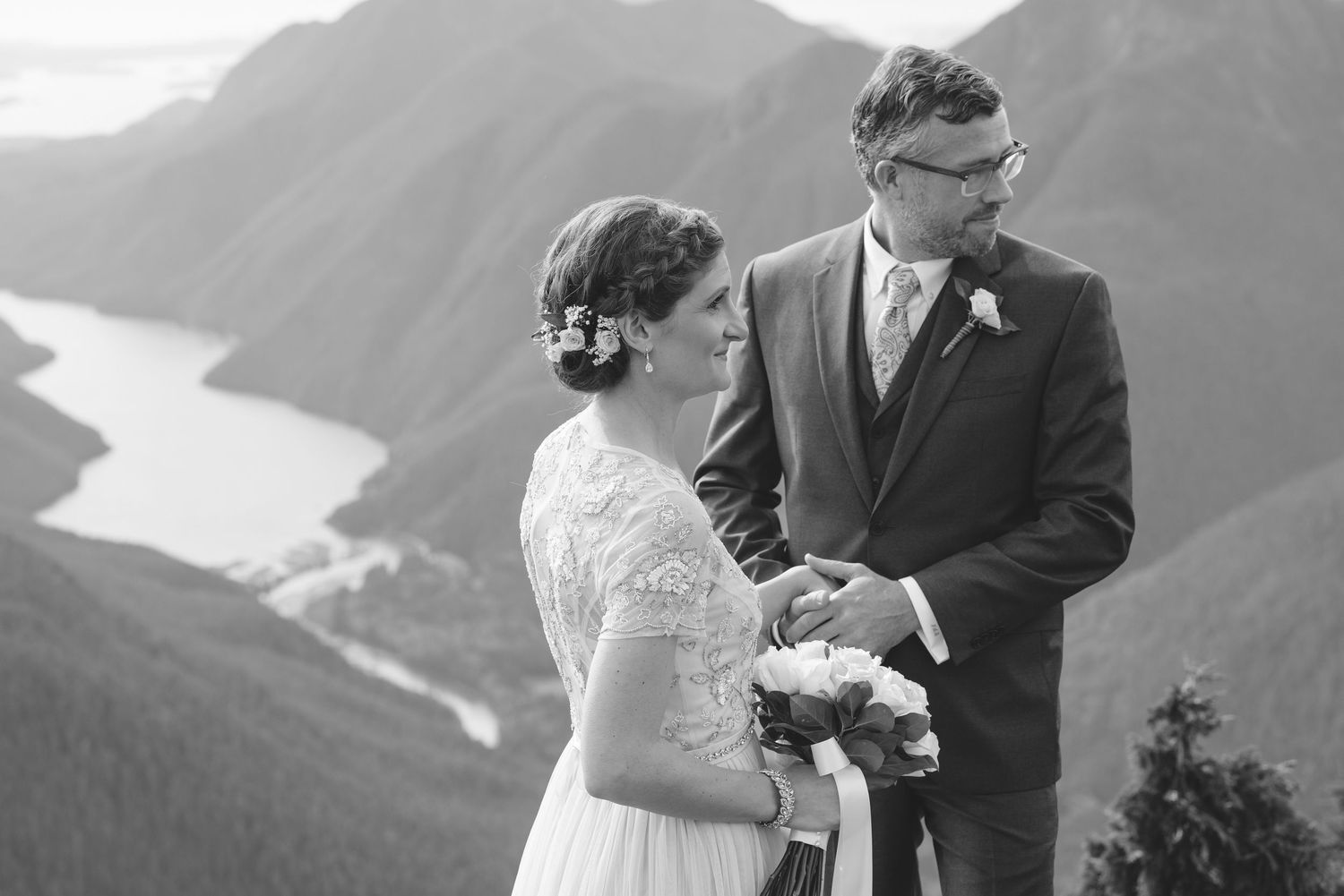 A couple shares an intimate moment during their mountaintop wedding ceremony with scenic mountain views.