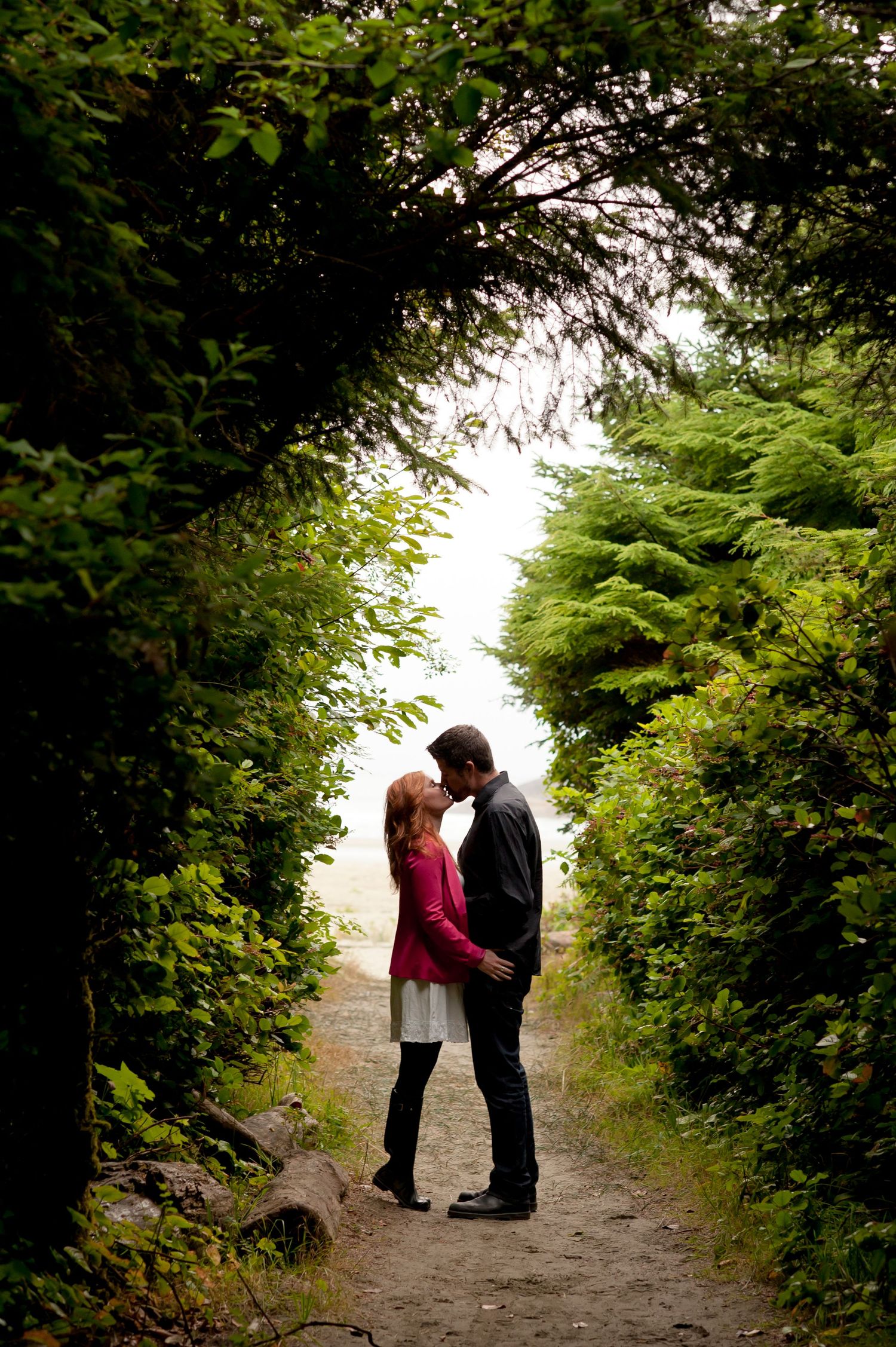 Romantic couple walking along tree-lined path during outdoor photo session.