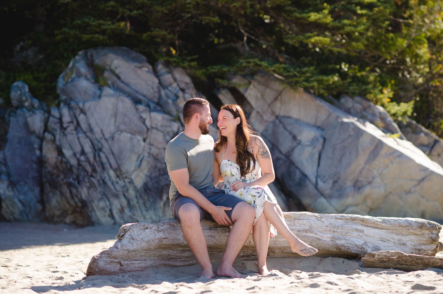 Relaxed family gathering on sandy beach with dramatic rocky coastline in background.