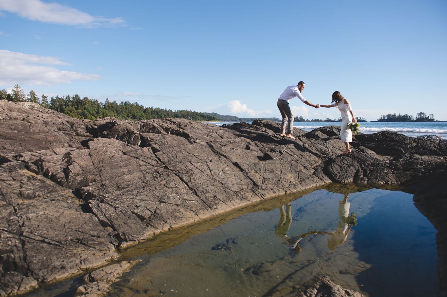 People exploring tidal pools and rocky formations along scenic coastal shoreline.