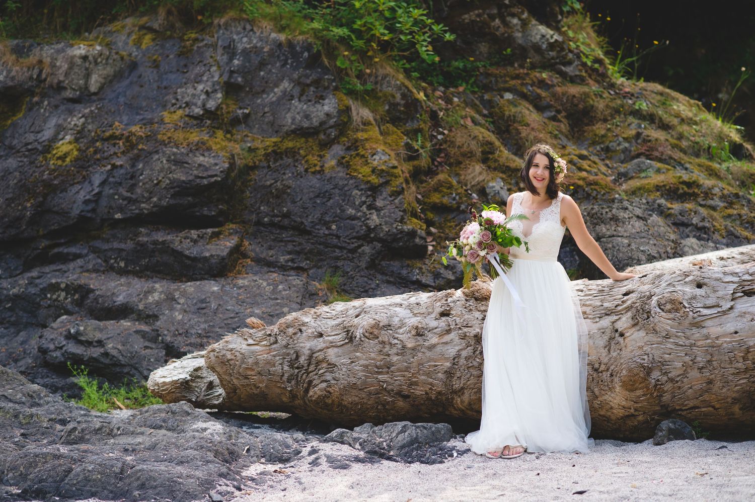 Wedding photography on rocky beach with dramatic cliff backdrop and natural scenery.