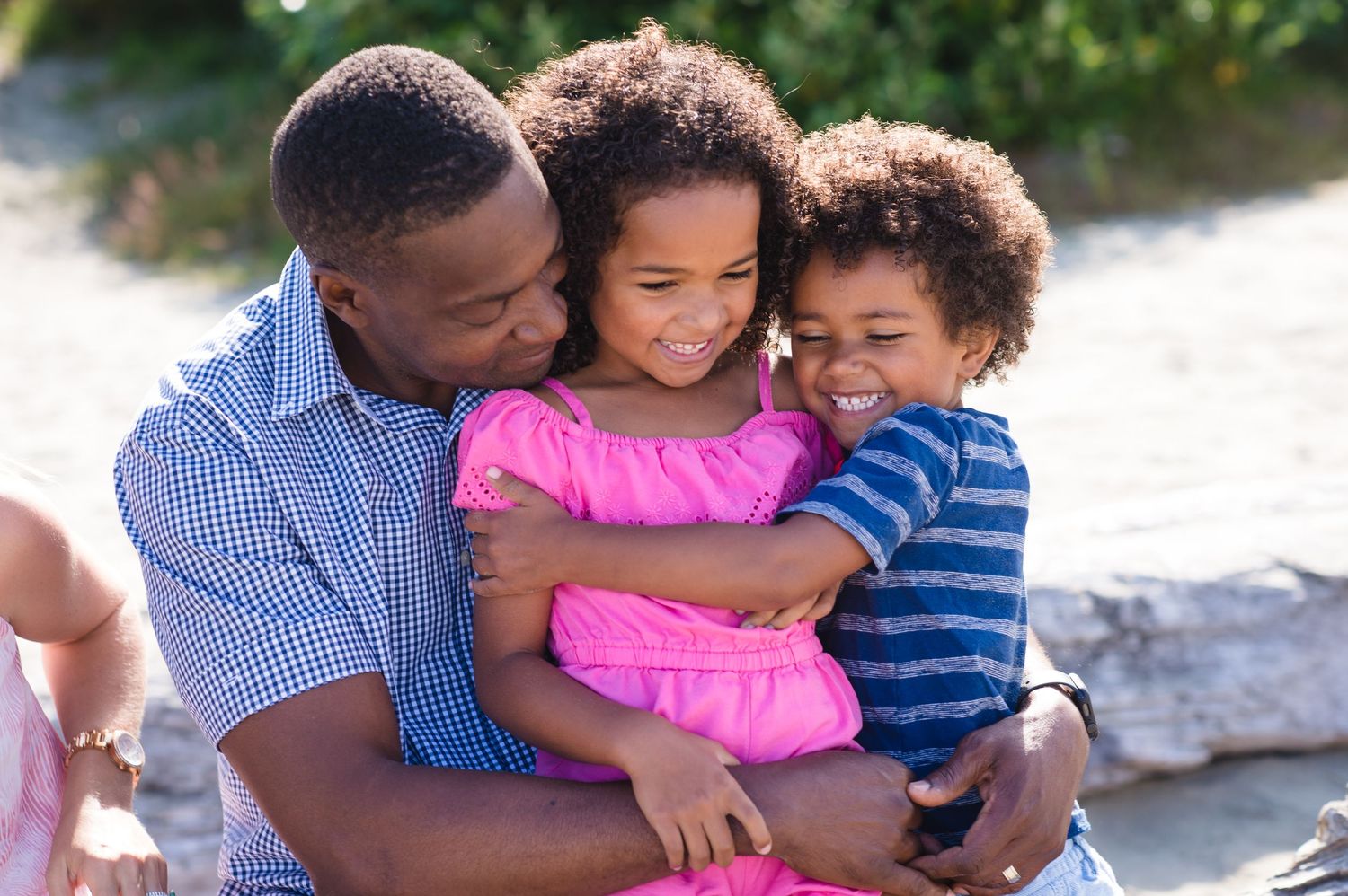 Happy family embracing and playing together outdoors in casual summer clothing.