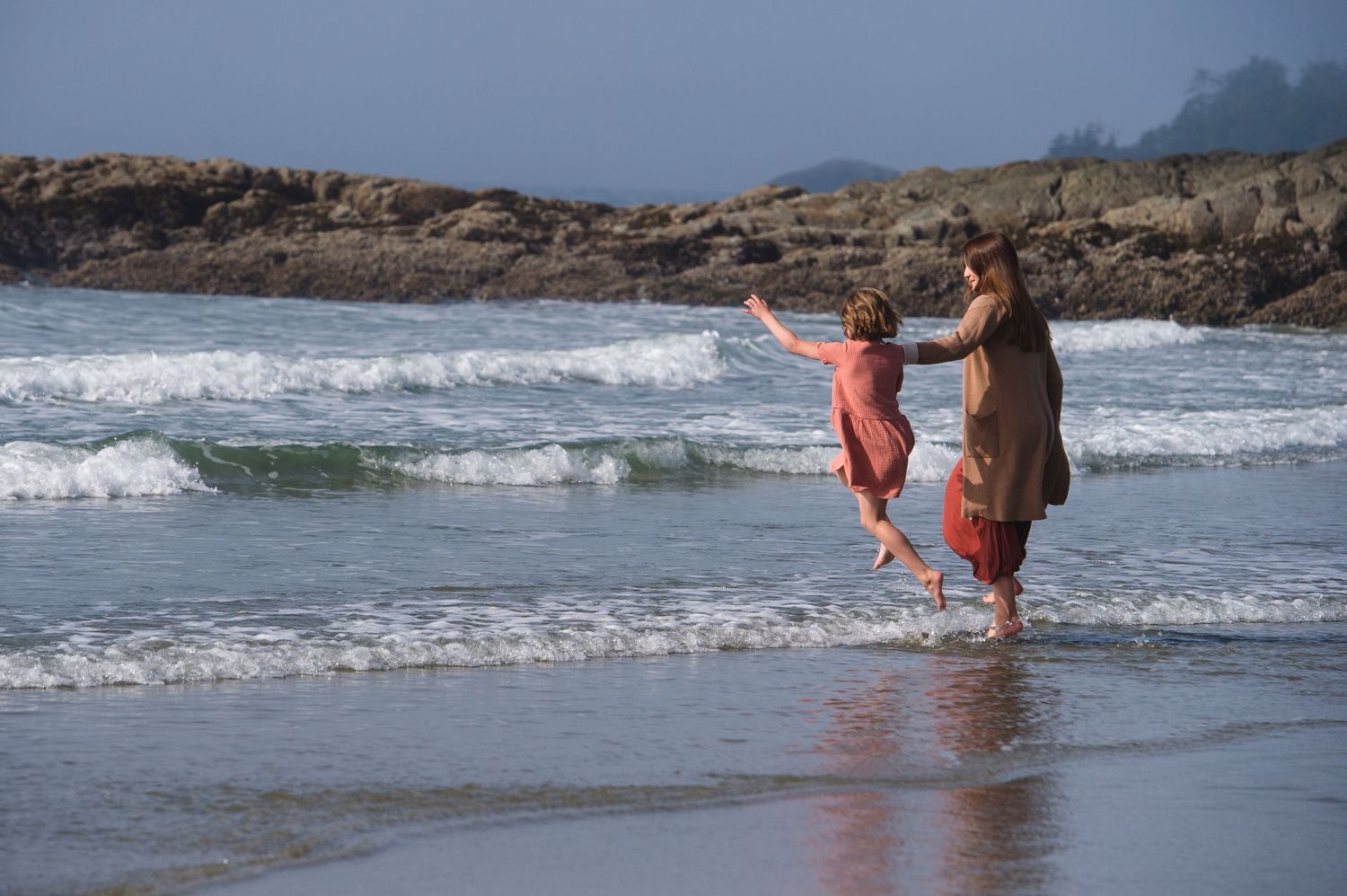 Group having fun running through incoming waves at a scenic beach.