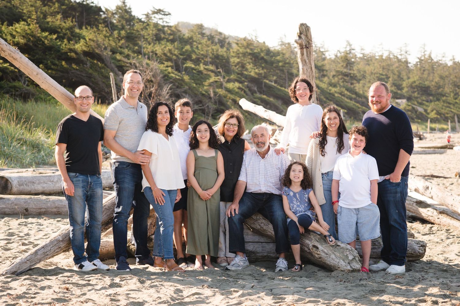 Group portrait of family members arranged on large beach logs at sunset.