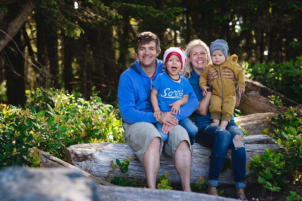 Family group sitting together on rocks surrounded by lush green forest.