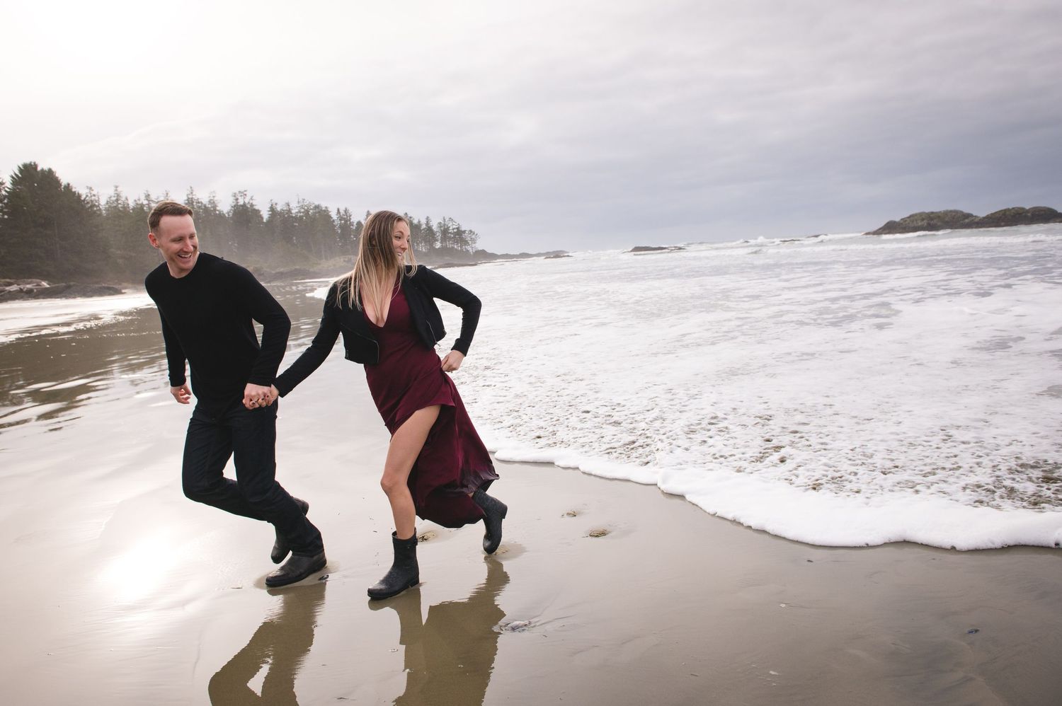 Couple playing and splashing in ocean waves along scenic beach.