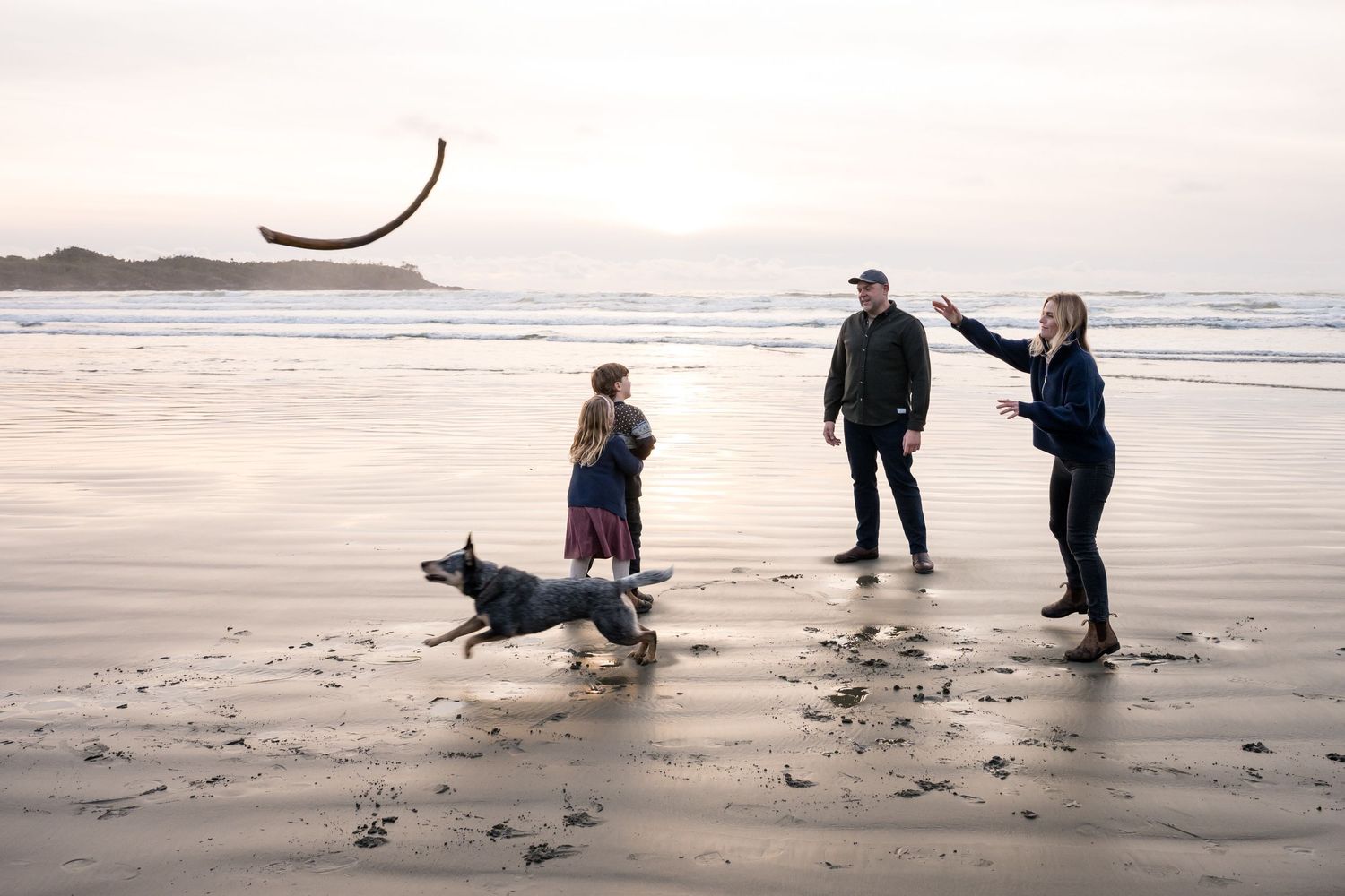 Group enjoying leisure time on a sandy Pacific Northwest beach at dusk.