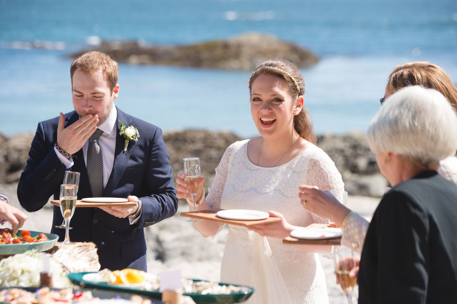 Wedding reception guests mingling and toasting at a seaside celebration.