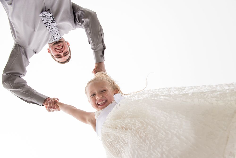 Bride and groom playing in ocean surf at beach wedding.