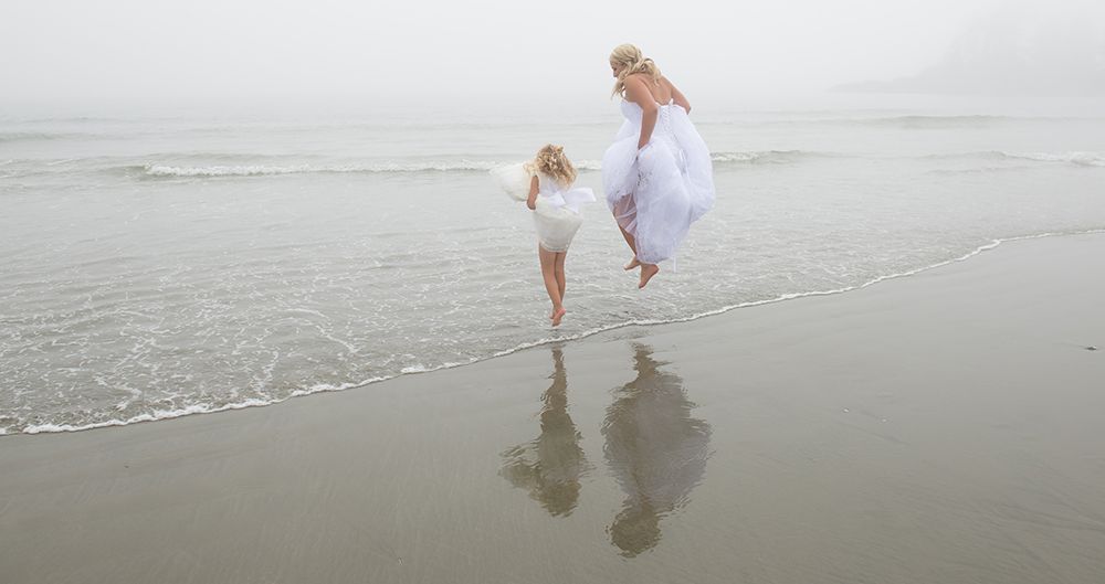 Couple walking together along ocean shoreline leaving footprints in wet sand.