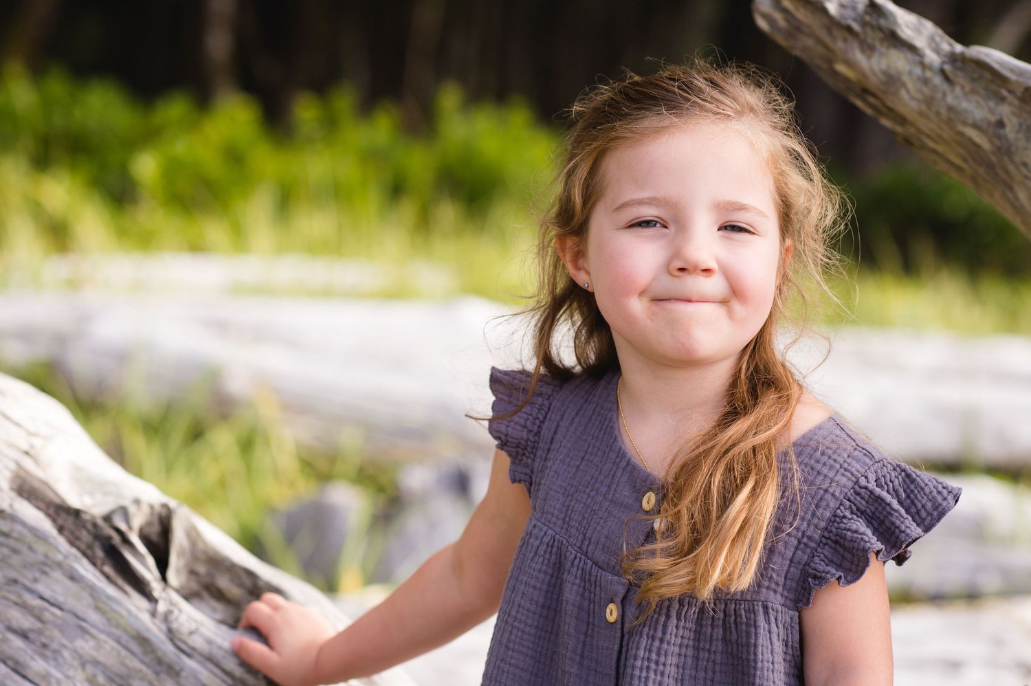 Summer beach portraits captured against natural driftwood backdrop.