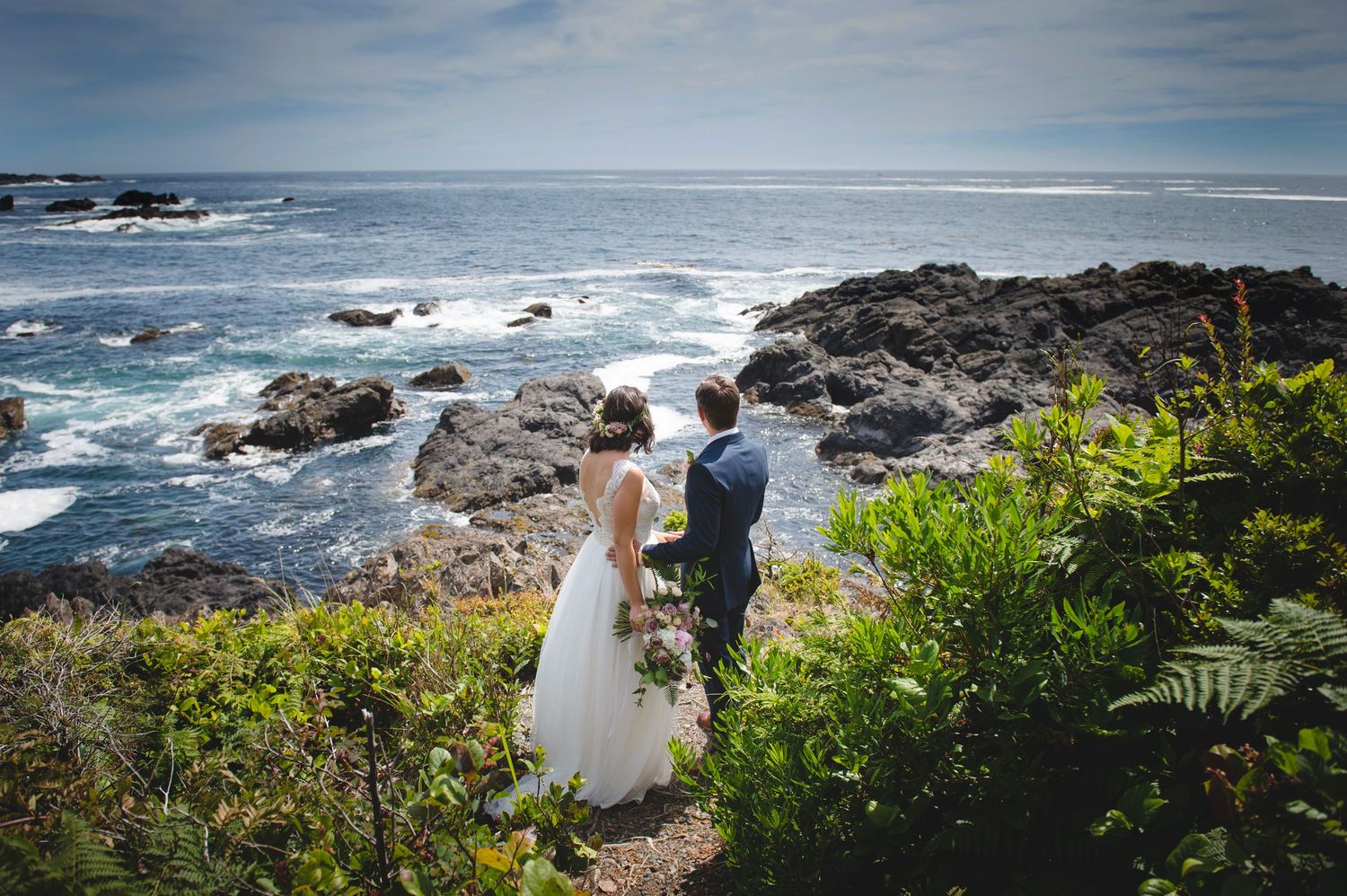 Wide panoramic view of a rocky coastline during a wedding ceremony.