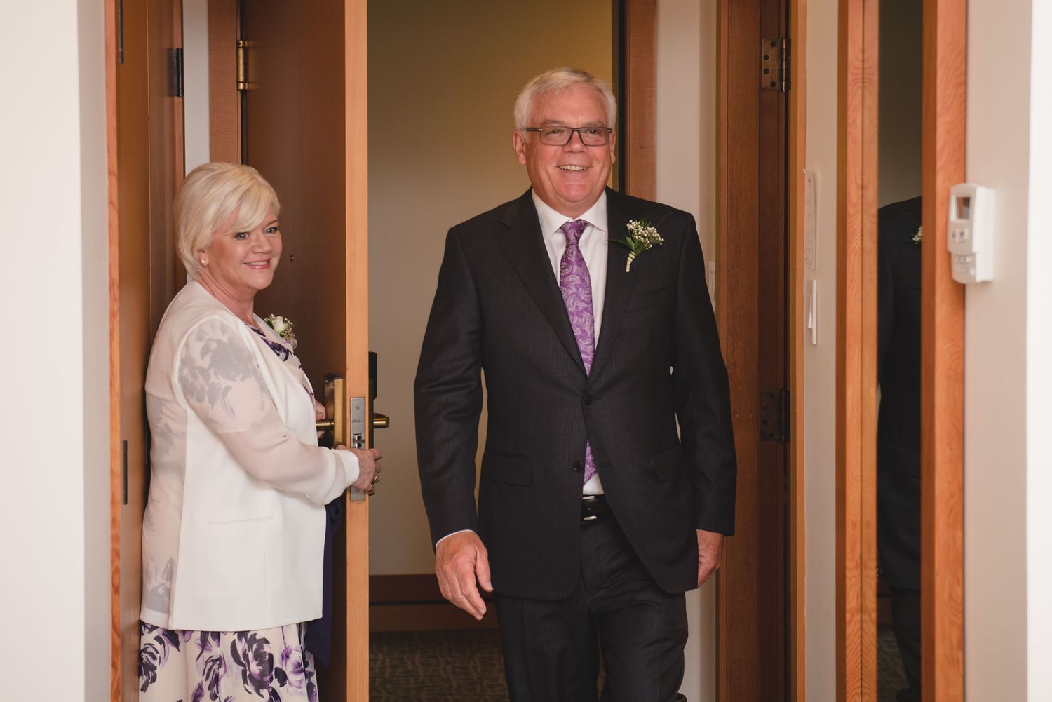 Wedding party members standing in a hallway with wooden doors.