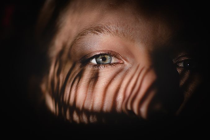 Dramatic shadows create pattern effects in dark moody portrait lighting.
