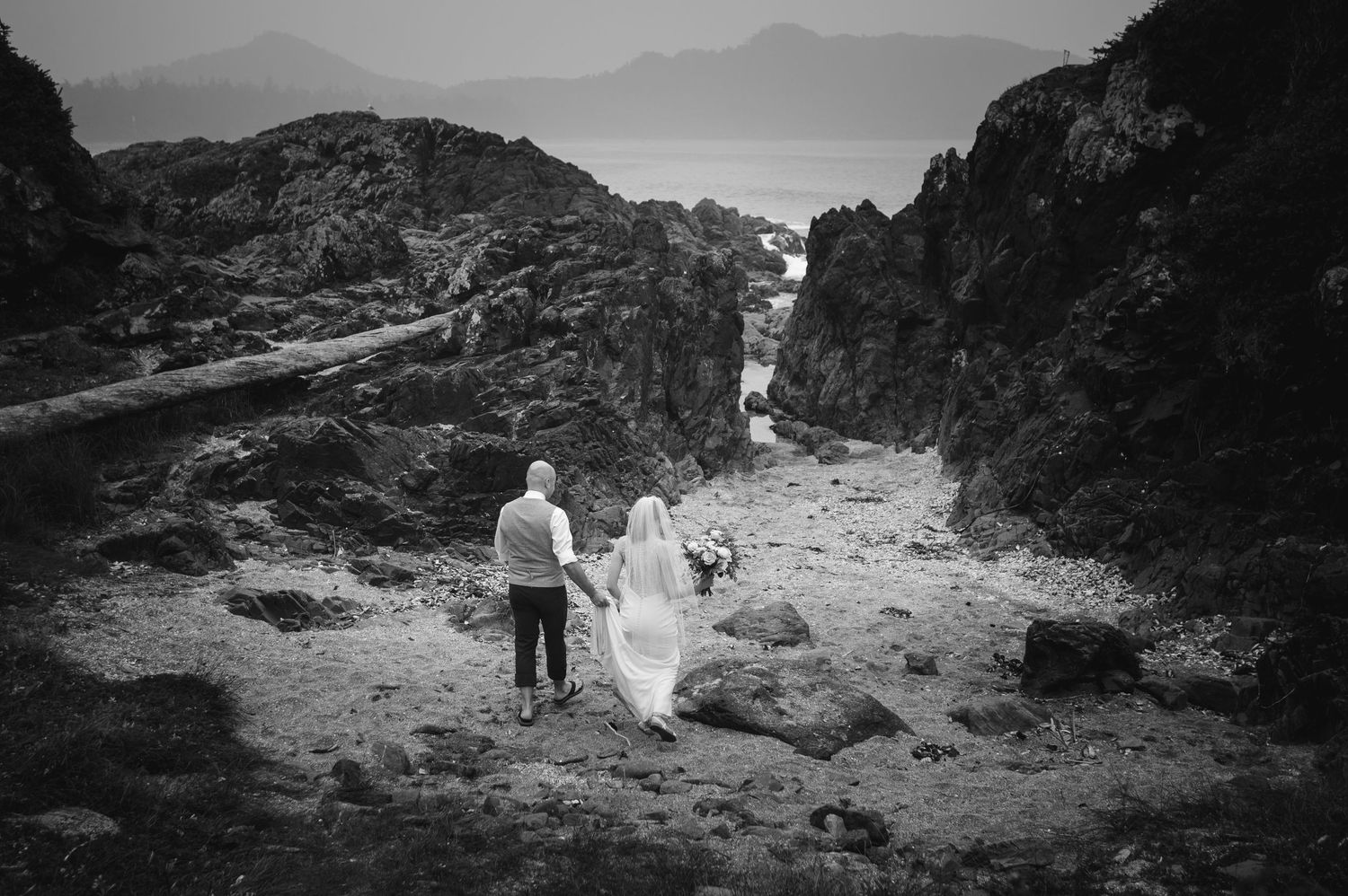 Silhouettes of people walking along rocky mountain terrain against a misty landscape backdrop.
