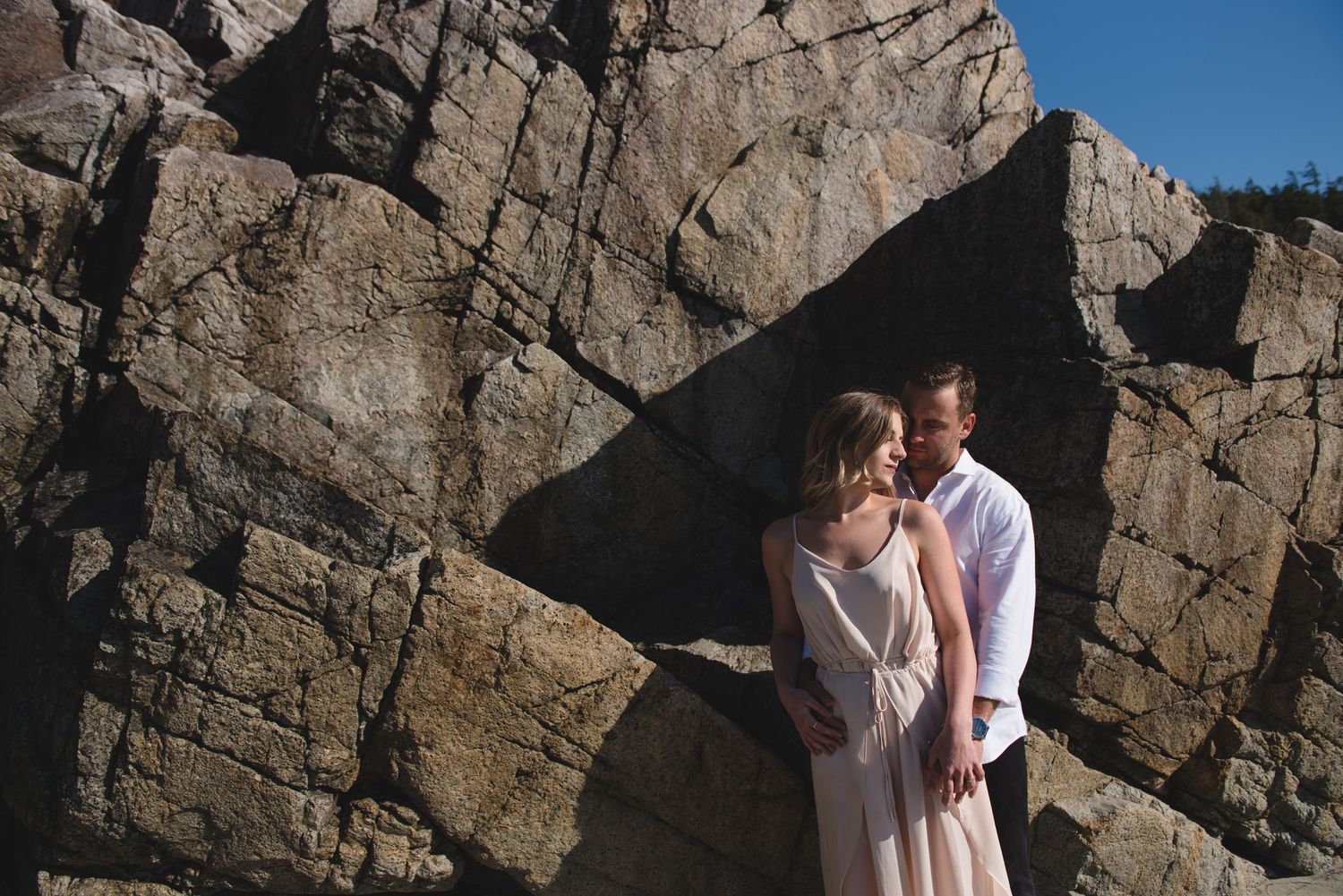 A couple shares an intimate moment against a rocky cliff face in a series of connected photos.