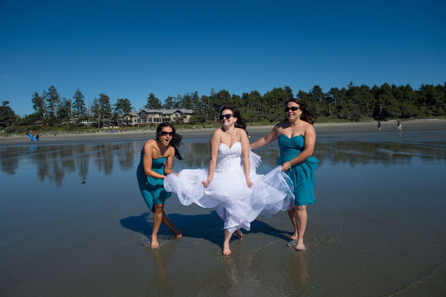 Wedding party having fun on a scenic beach with blue skies and ocean views.