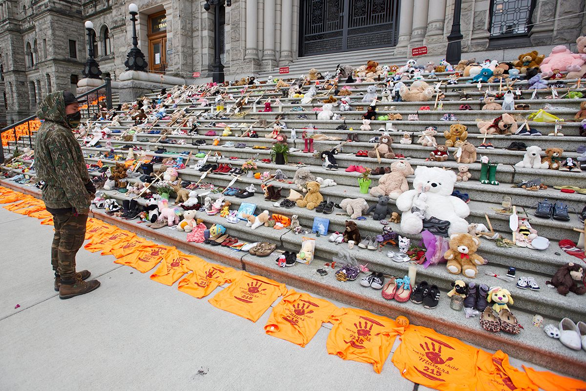 Rows of orange and white protest signs laid out on stone steps of a building.