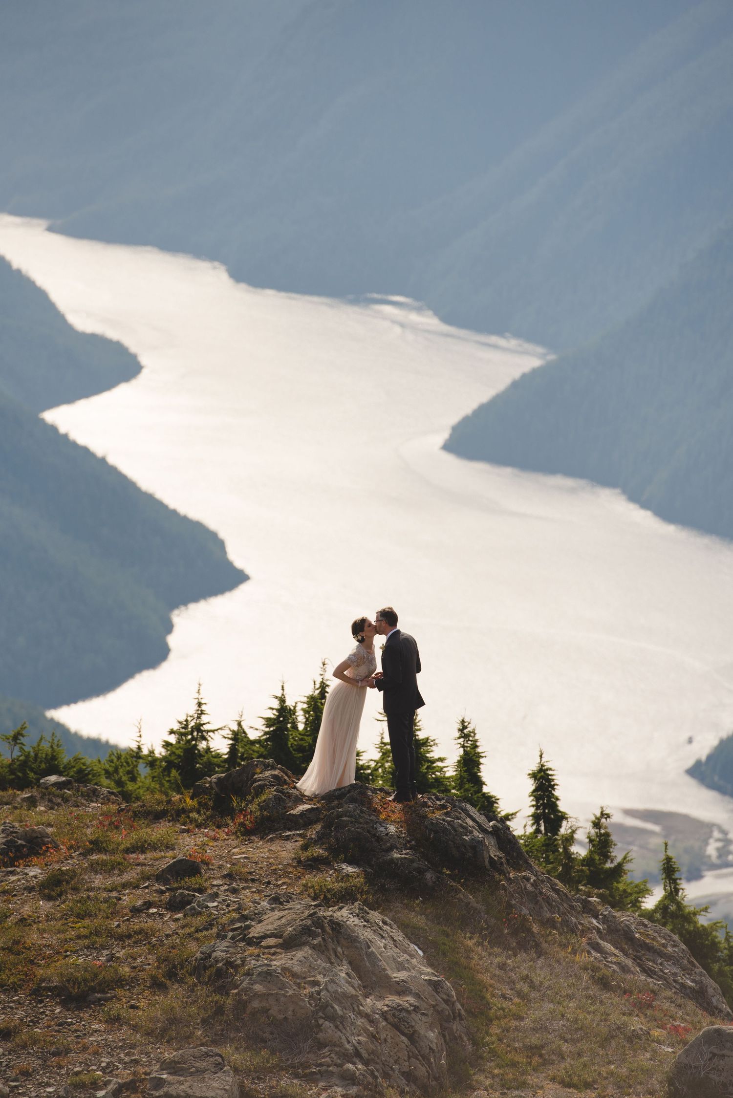 Silhouettes against bright mountain lake view from scenic overlook.