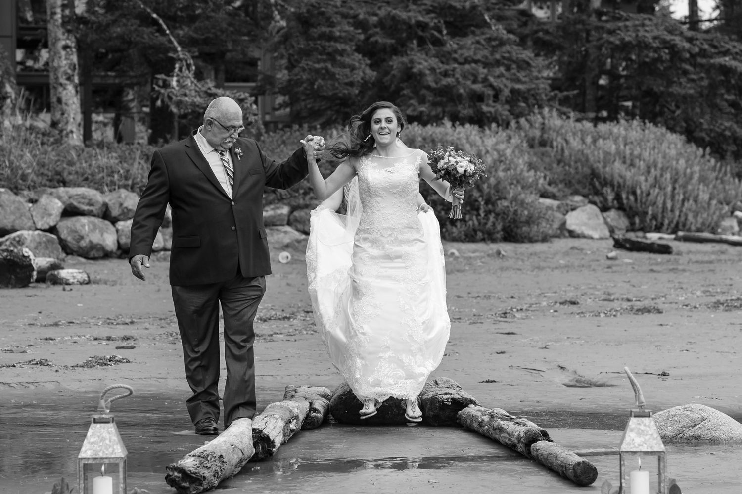 Black and white photo of playful moment balancing on logs near water.