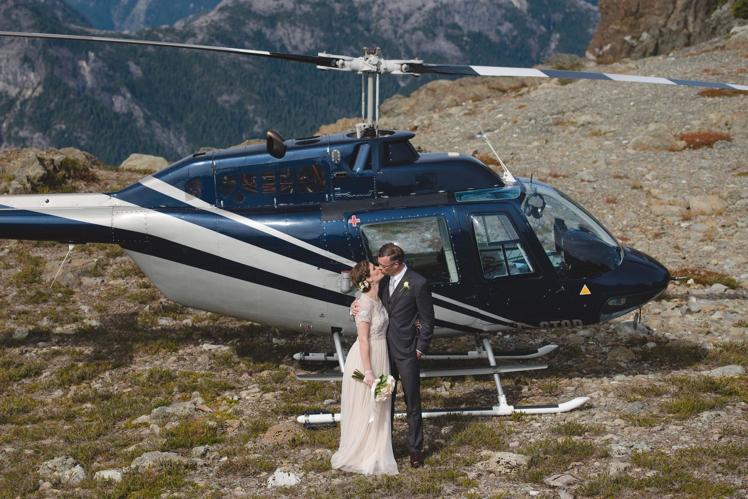 Helicopter parked on a mountain summit with sweeping alpine vistas.