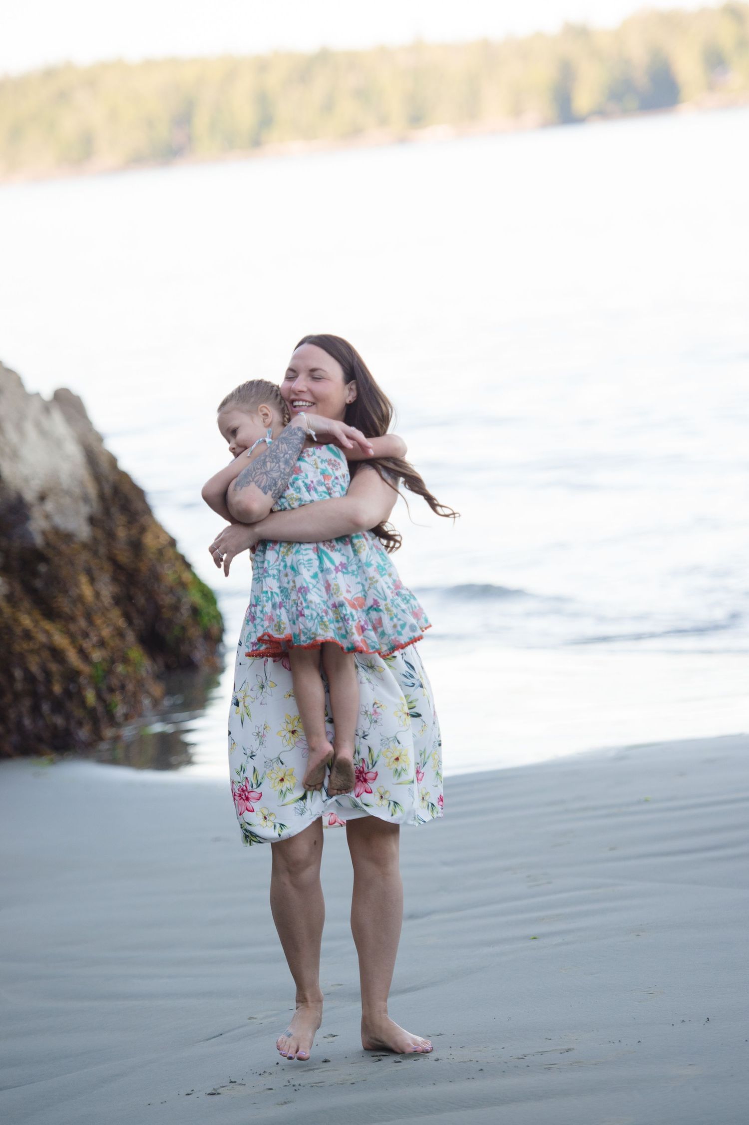 Playful moments captured between two people in floral outfits on a sandy beach.