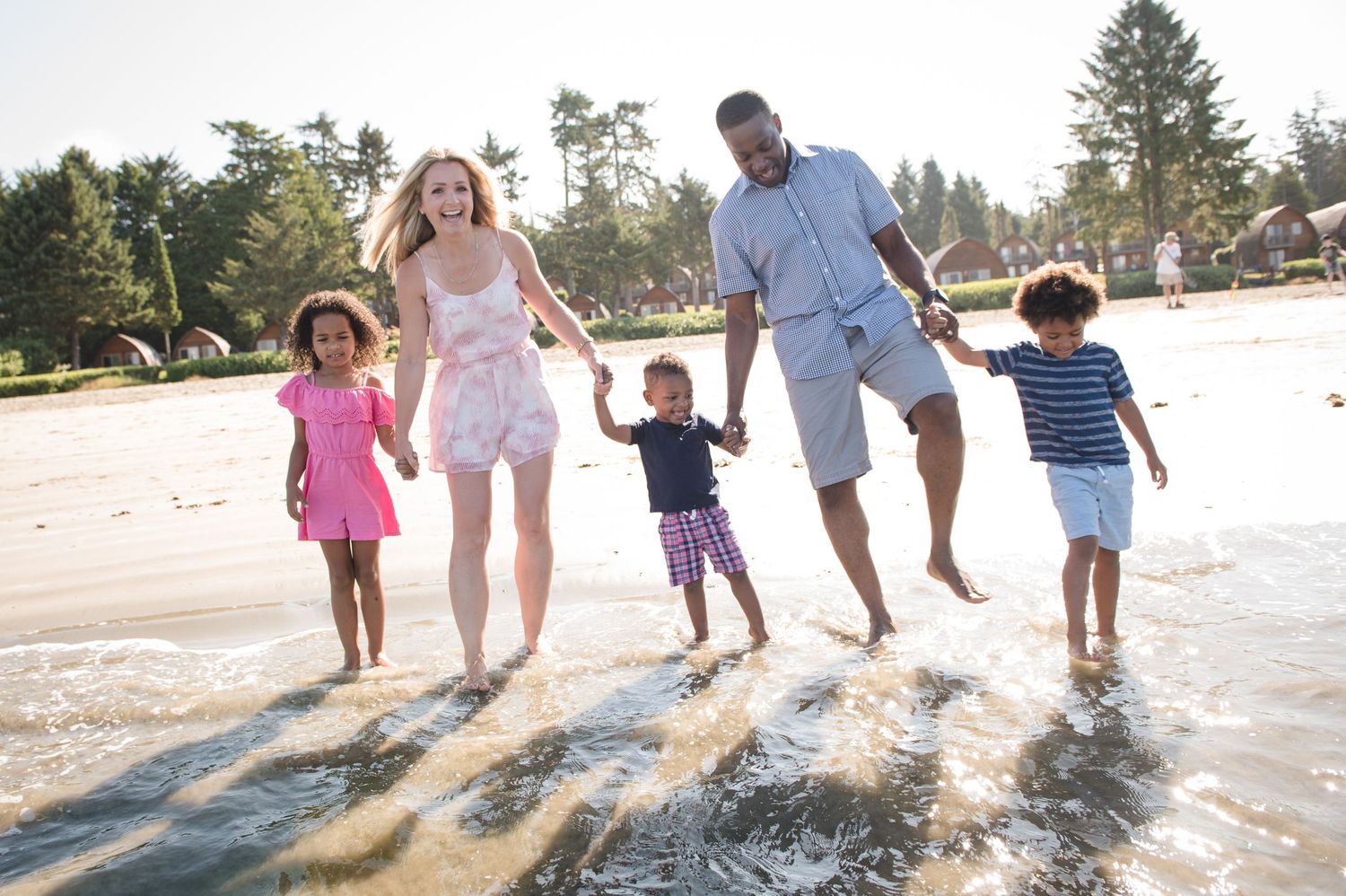 People splashing and playing in shallow beach water during a fun summer day.