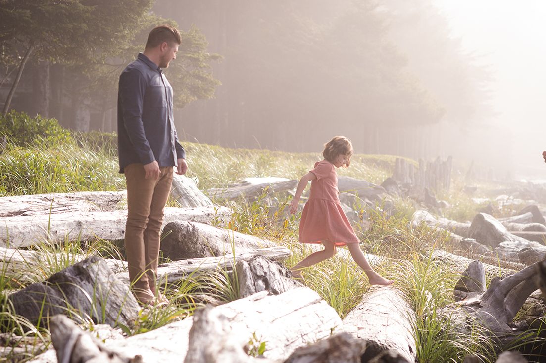 Family hiking together on a misty mountain trail during golden hour sunset.