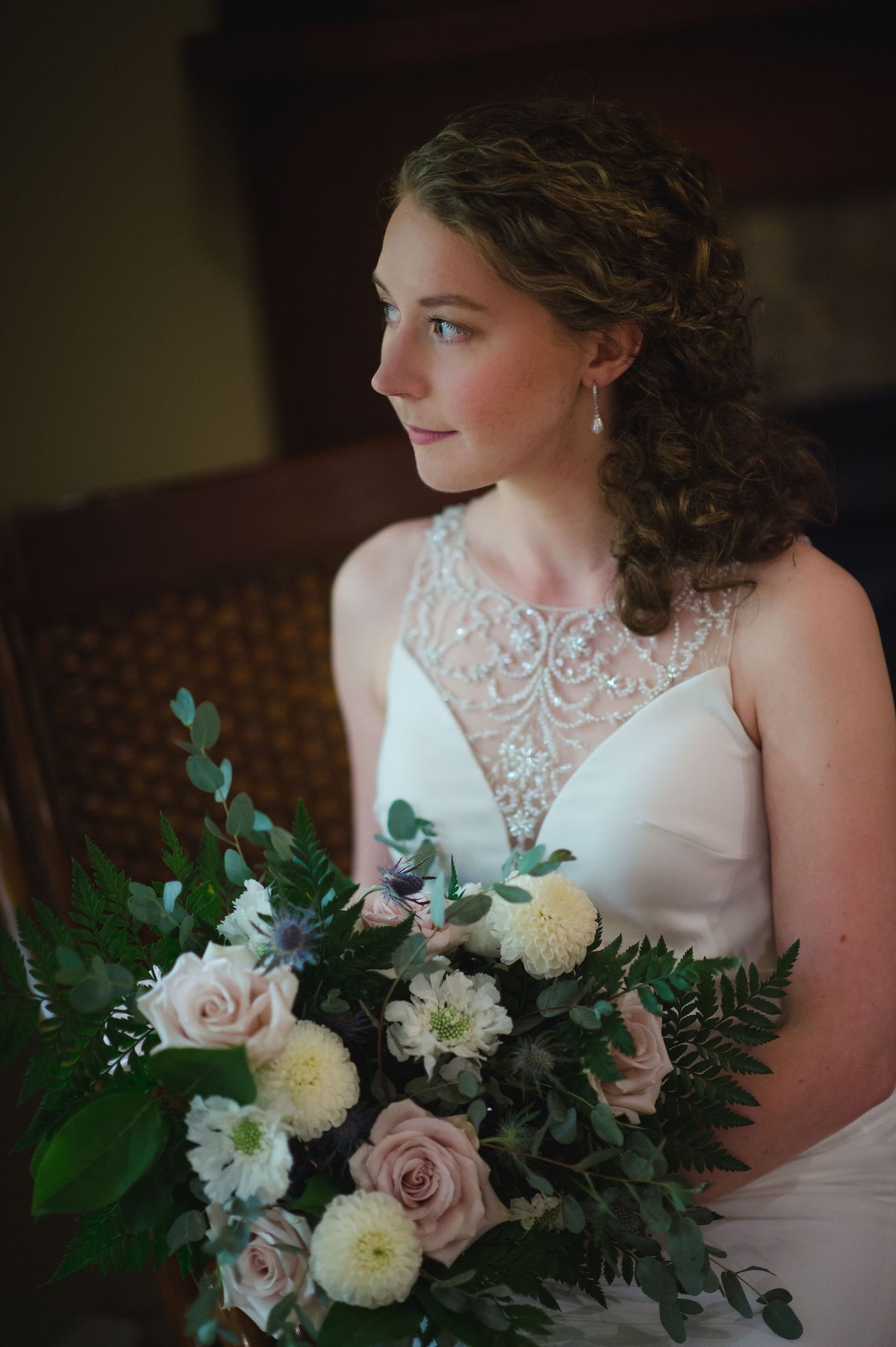 Elegant bridal portrait featuring a lace neckline dress and romantic bouquet with blush roses and white flowers.