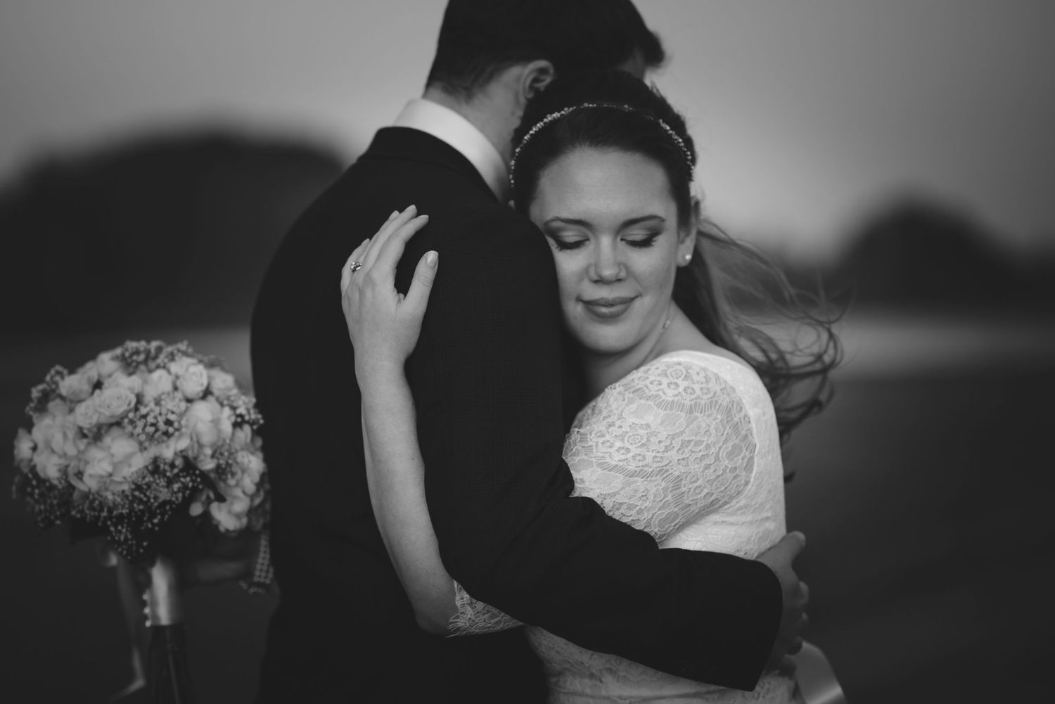 An intimate black and white portrait of newlyweds in an embrace.
