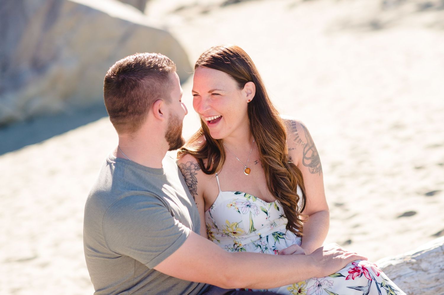 Intimate beachside moment captured during golden hour against rocky coastal backdrop.