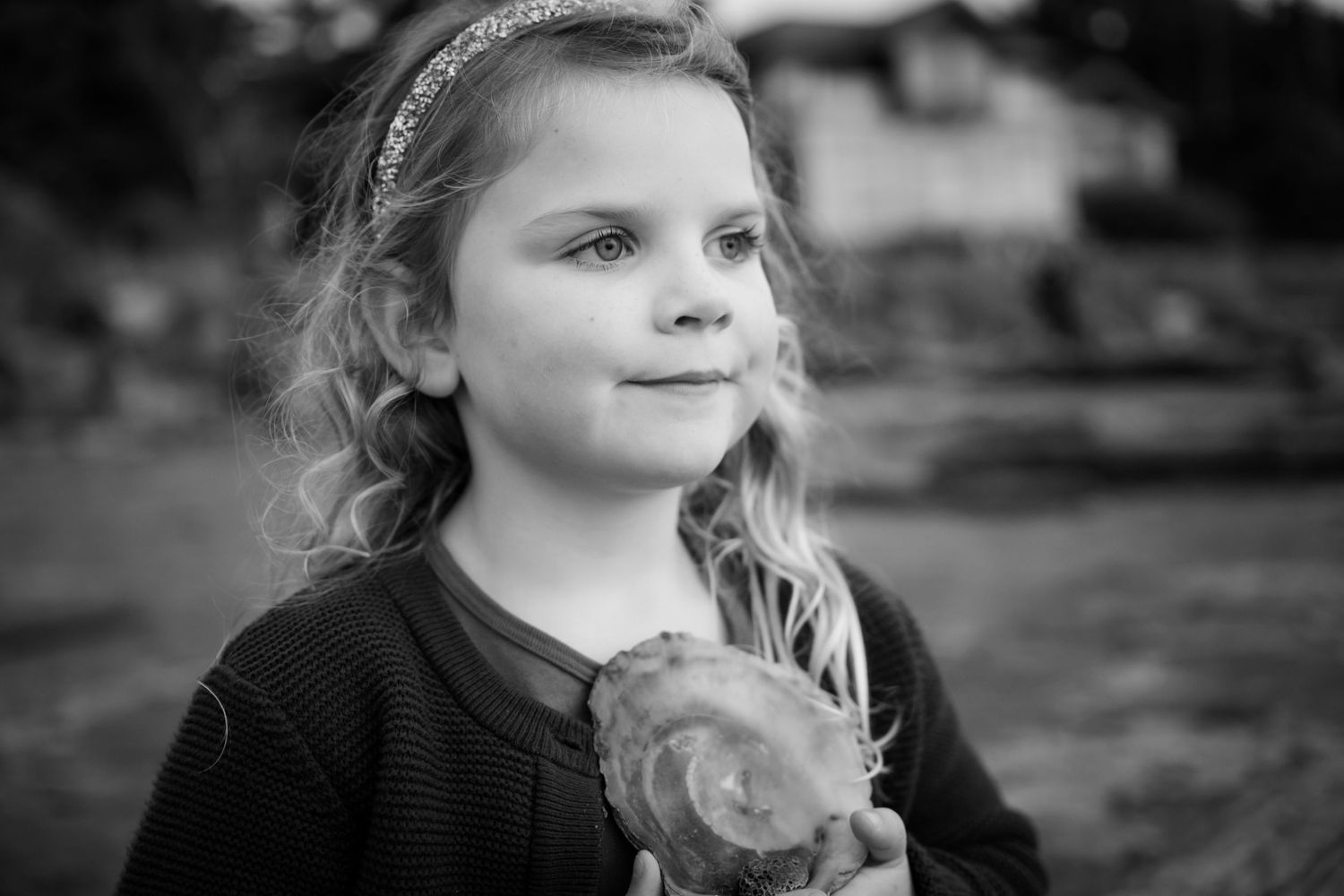 Black and white portrait of a young child holding a treat outdoors.