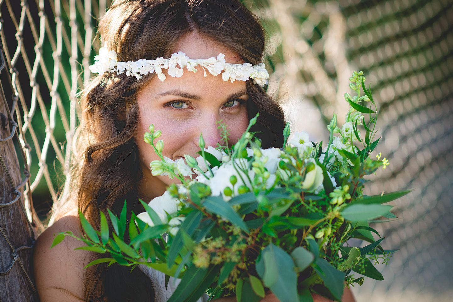 Delicate floral crown with white flowers and green leaves in soft natural light.