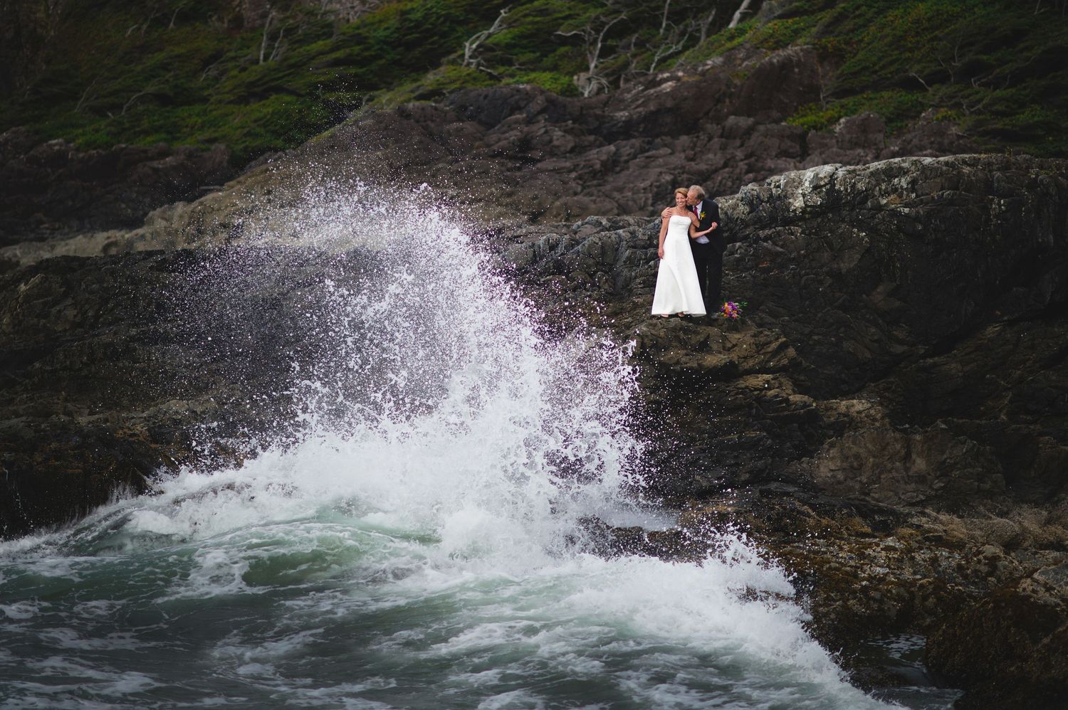 Dramatic waves splashing against dark rocky shoreline.
