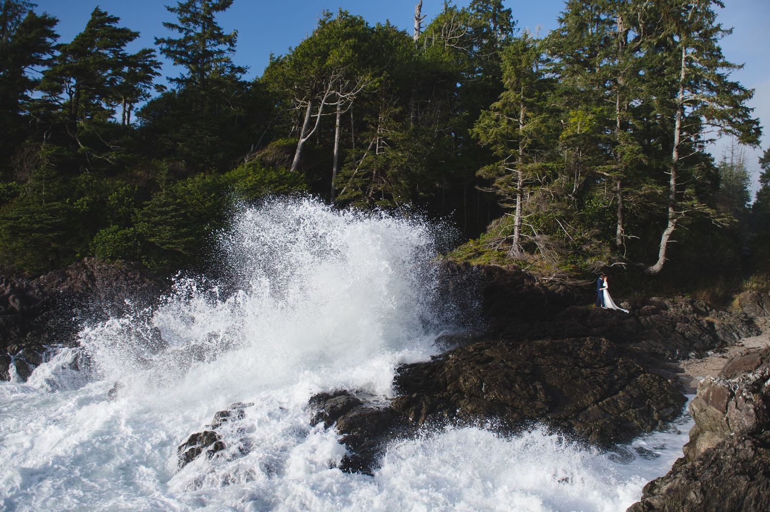 Dramatic waves crash against rocky cliffs along a Pacific Northwest coastline.