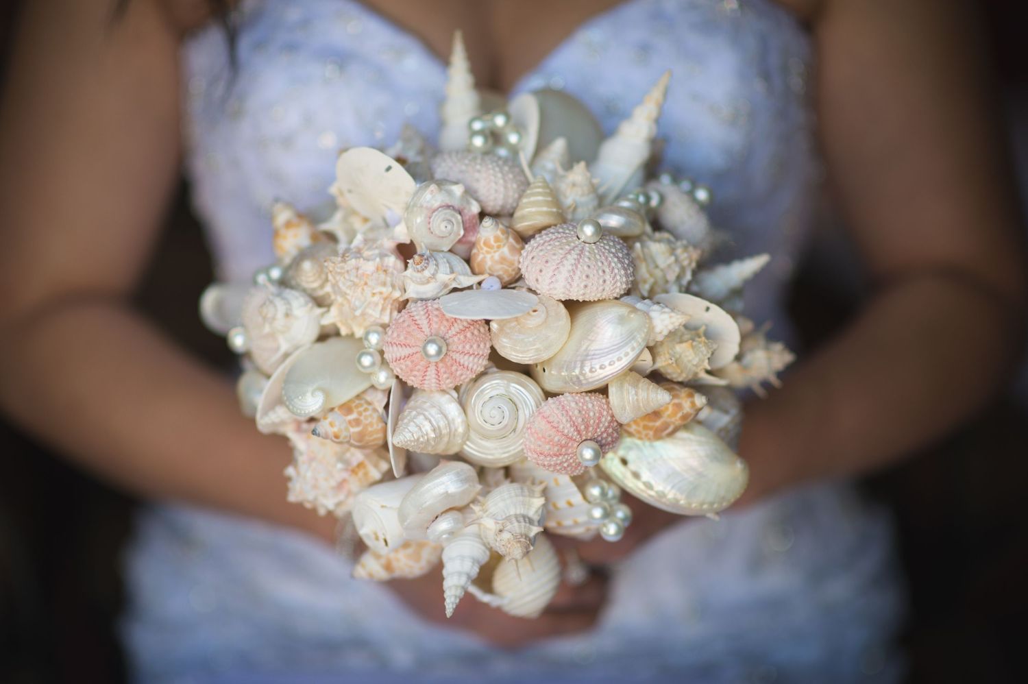Delicate seashell and flower bouquet in soft pink and white tones.
