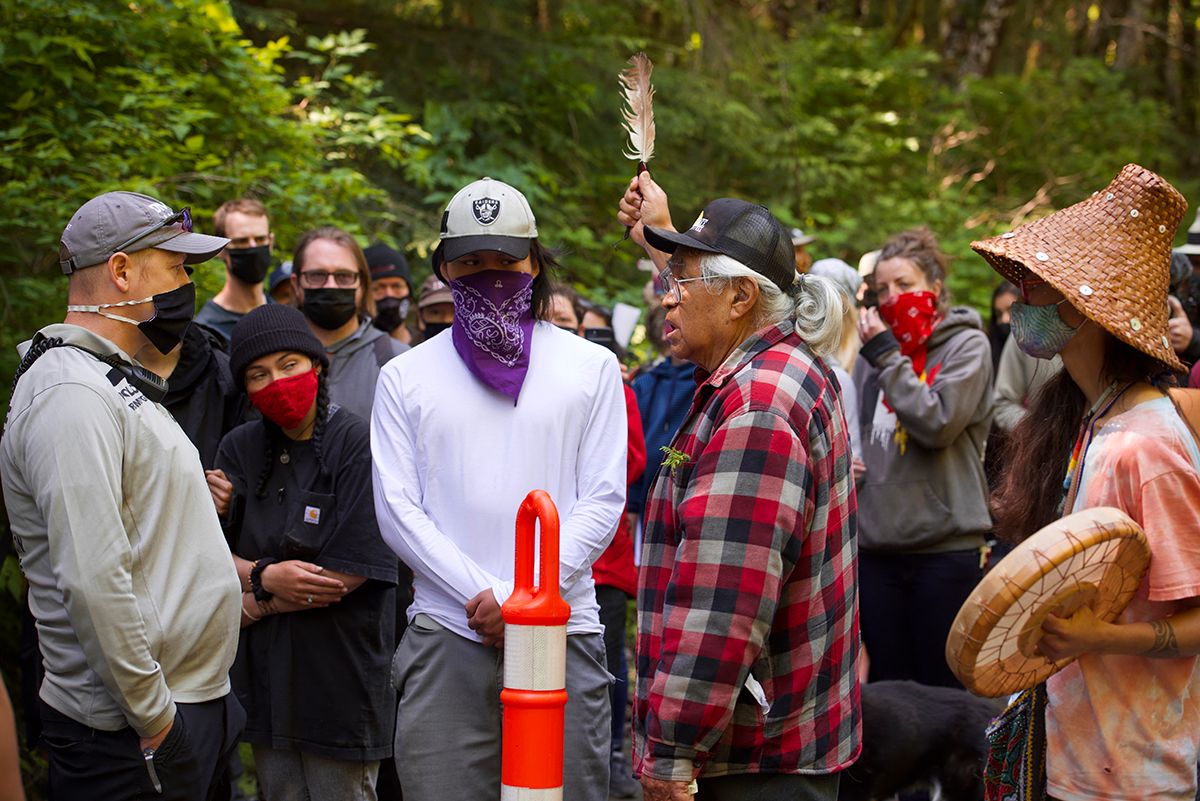 Fairy Creek blockade. A crowd of people gathered outdoors wearing masks and casual clothing in a forest setting.