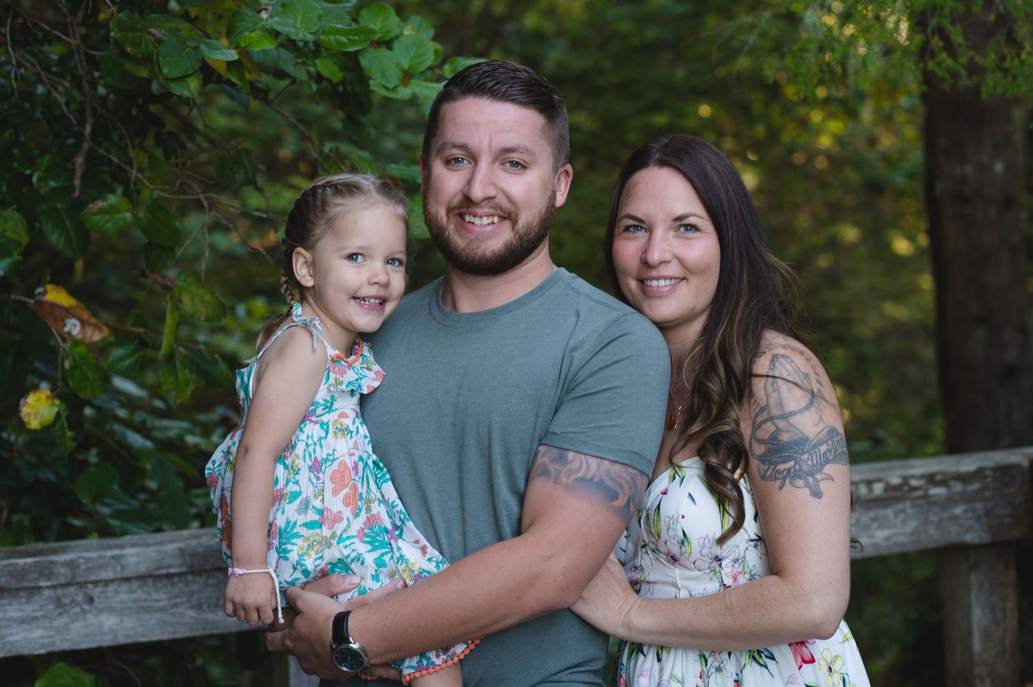 Family portrait session in a lush green forest setting at golden hour.