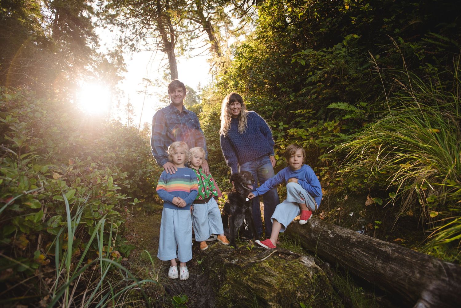 Golden sunlight streams through forest trees illuminating a family gathering in the woods.