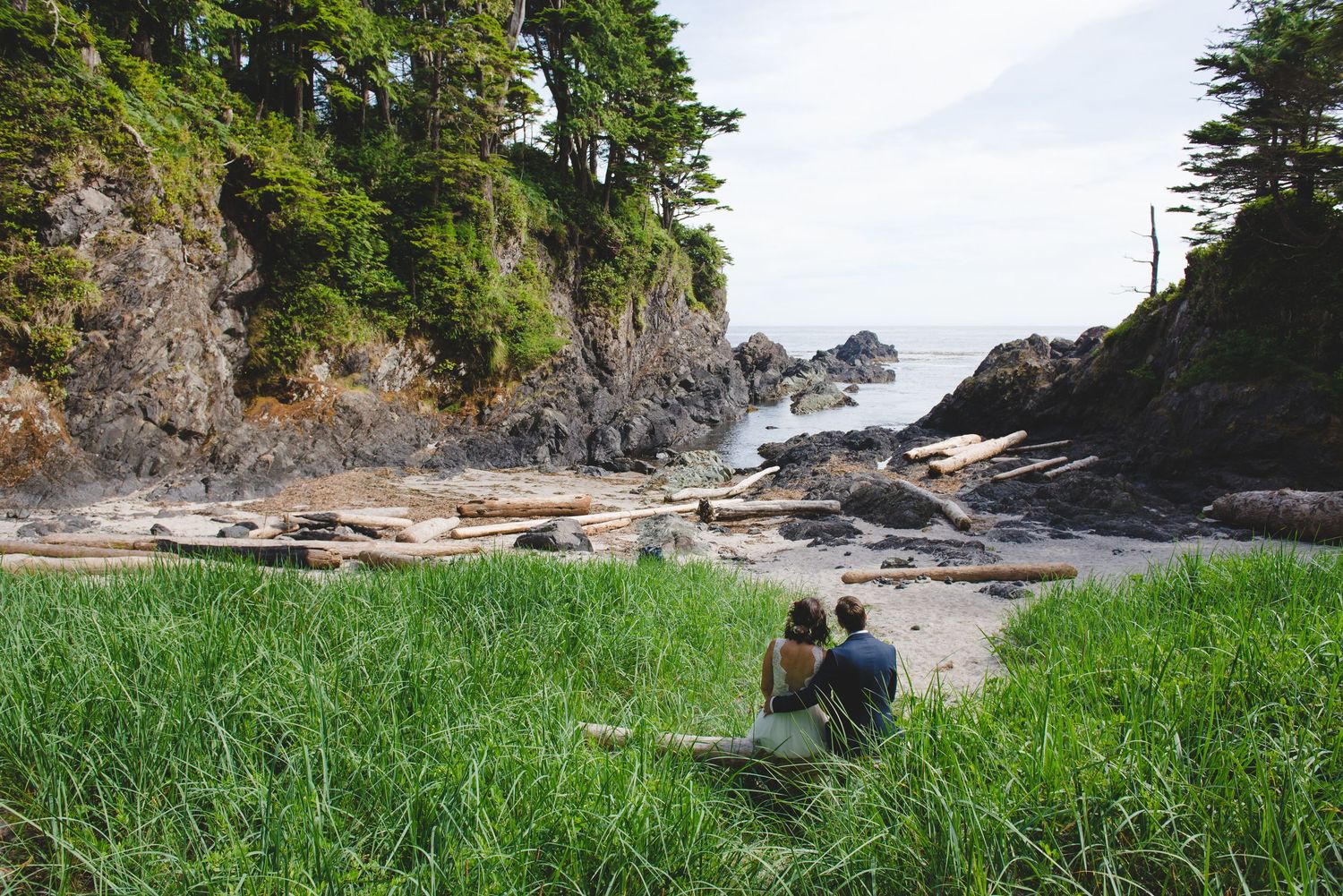 Wedding photography session along rugged Pacific Northwest coastline with evergreen trees.