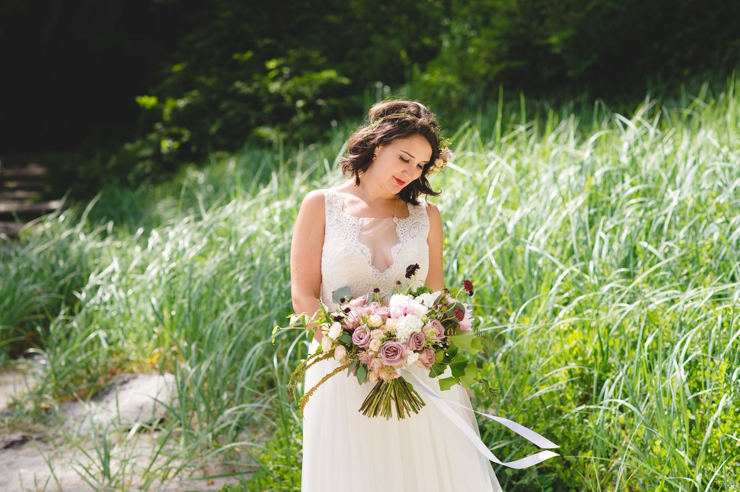 White wedding dress photographed against lush green grass and natural scenery.