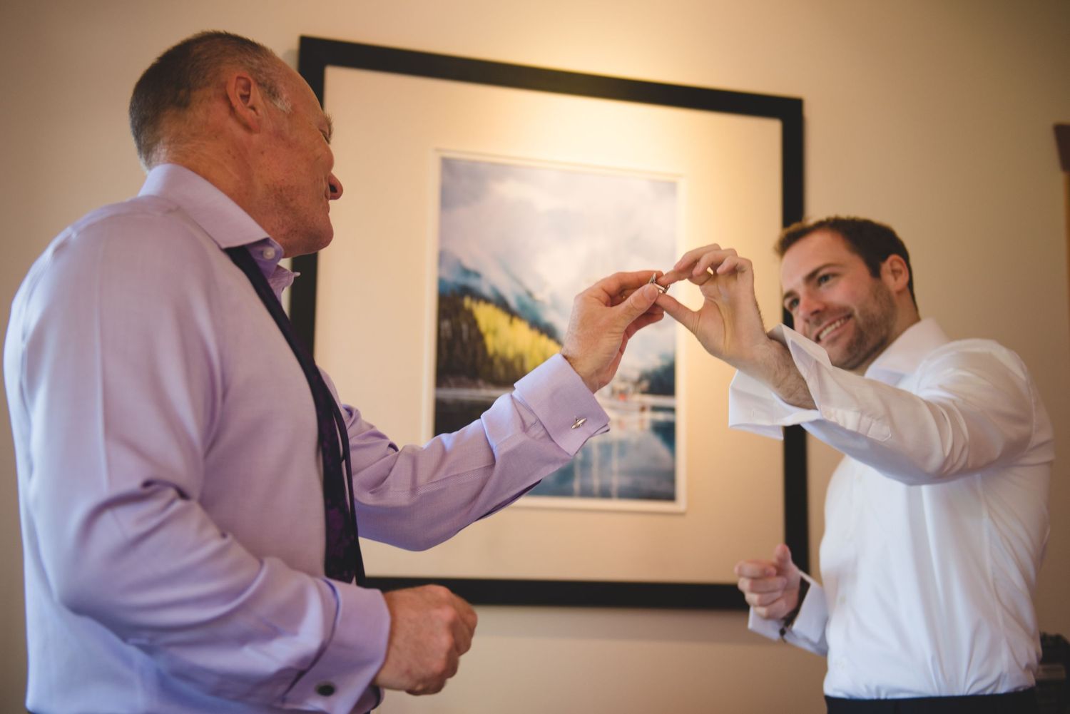 Wedding preparations showing men adjusting formal attire indoors.