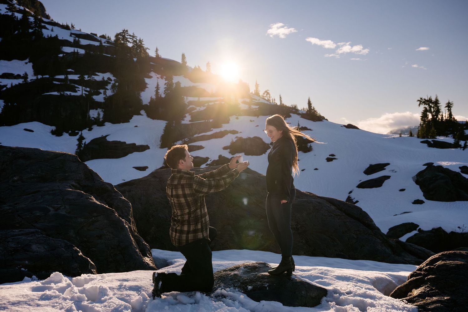 Person proposing on one knee to partner at golden hour in snowy mountains in Tofino during a helicopter proposal.