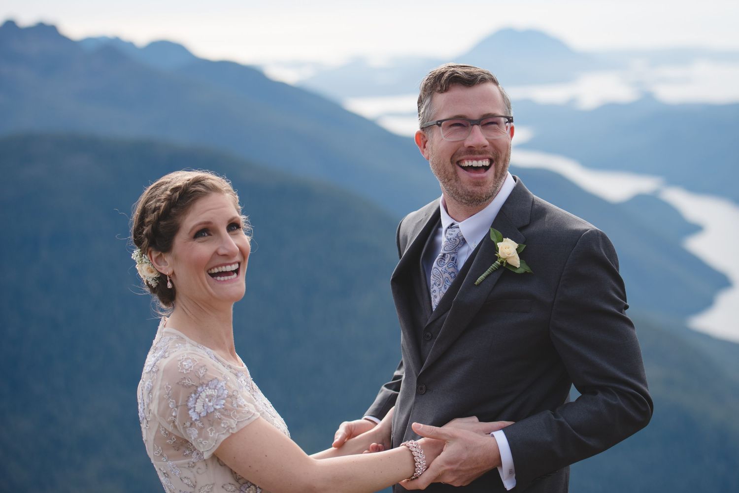 A couple laughs joyfully during their outdoor mountain wedding ceremony.