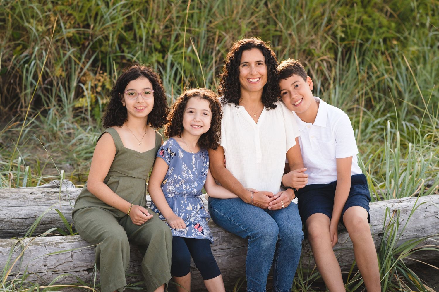 Family members arranged casually on beach driftwood for a natural outdoor portrait.