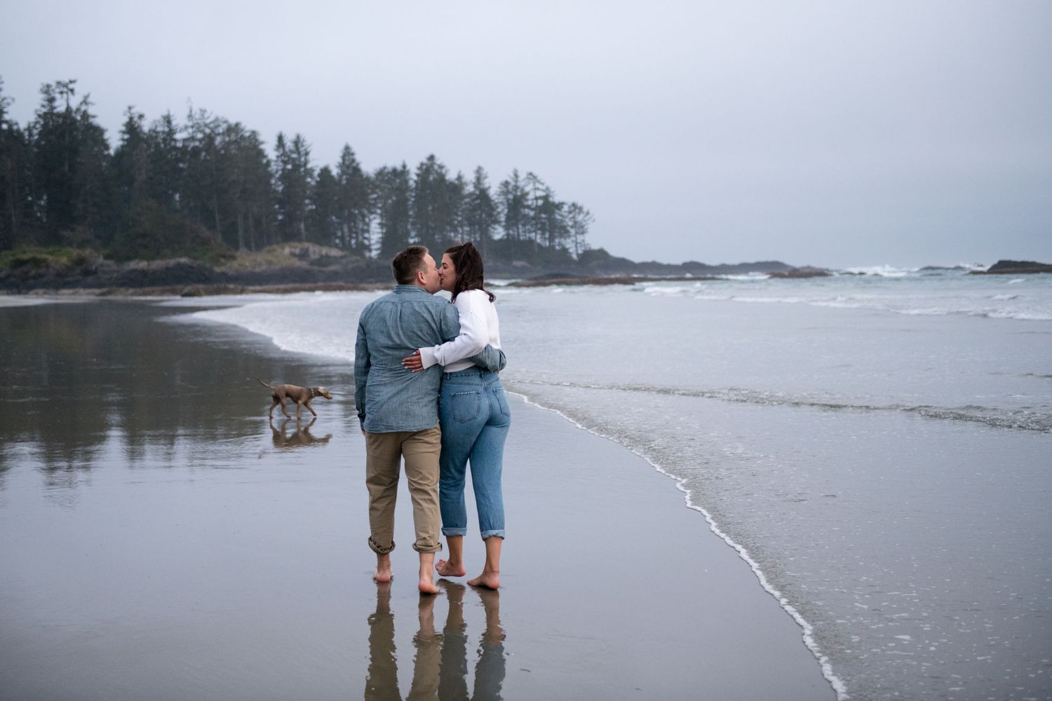 Couple shares intimate moment while walking along a scenic rocky coastline.